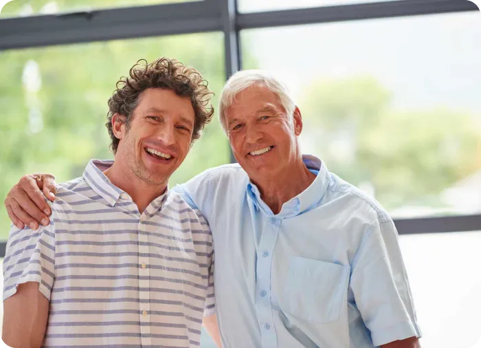 An older man and his adult son smiling together