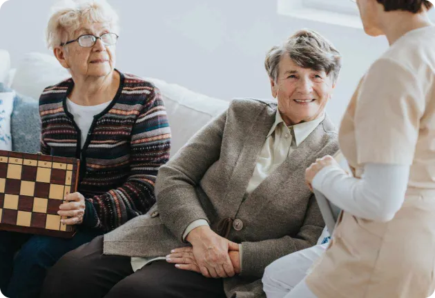Amanda Cassar speaking with two older women on a sofa